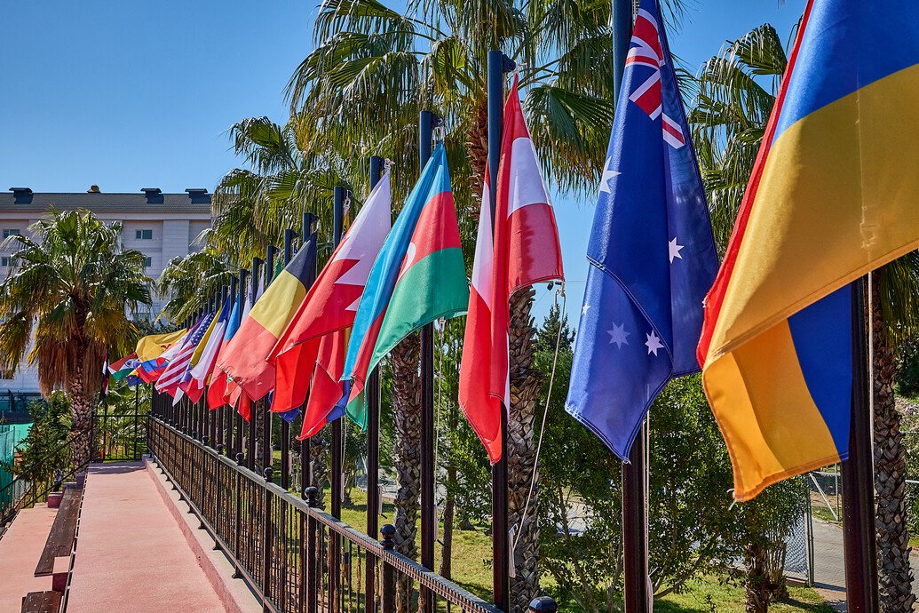 Drapeaux des nations devant un site de tennis international, illustrant le rôle mondial de l'instance qui devient World Tennis