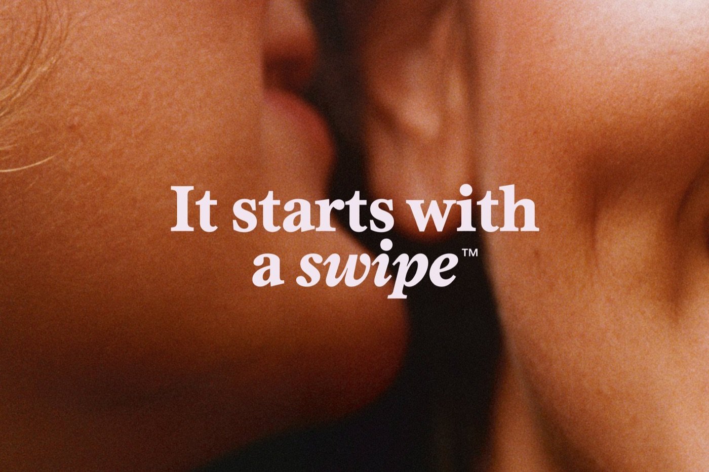 Campagne Tinder : gros plan sur deux visages qui s'embrassent, avec la signature It starts with a swipe en serif claire