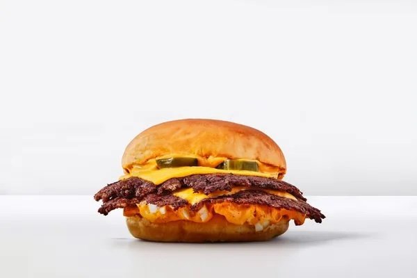 Un smash burger Starsmash présenté sur fond sombre, dans l'univers spatial de la marque